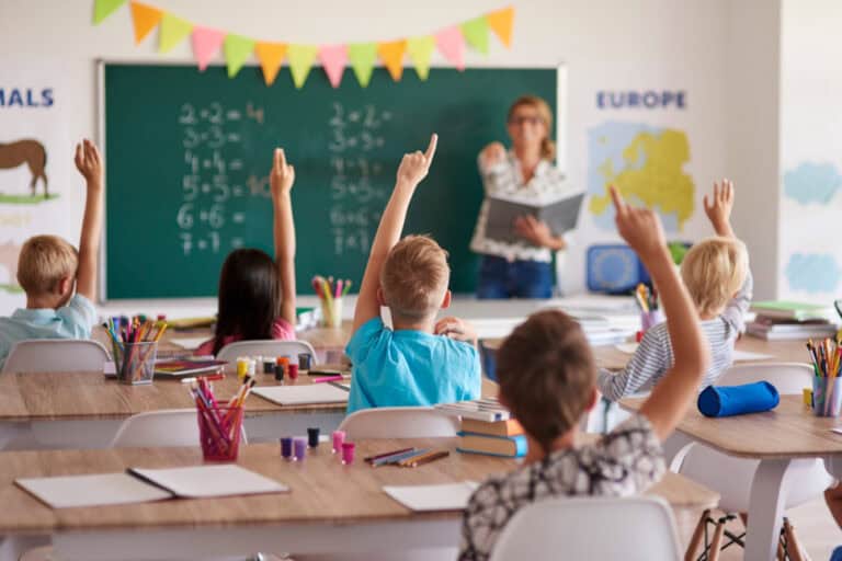 Gyerekek az iskolában, tanóra közben, a tanár kérdez.