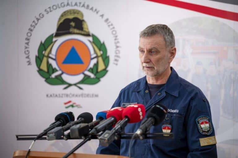 Védelmi szakember beszél a sajtó előtt, háttérben a Magyar Honvédség emblémája.