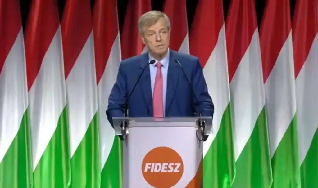 A magyar miniszterelnök beszédet mond a FIDESZ rendezvényén, háttérben magyar zászlók.