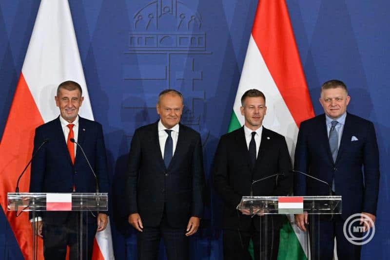 Négy férfi áll egymás mellett, háttérben magyar és uniós zászlók.