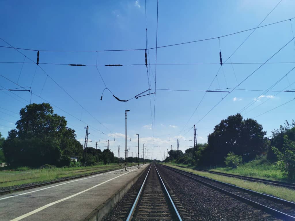 Vasúti sínpár és elektromos vezetékek a nyílt ég alatt.