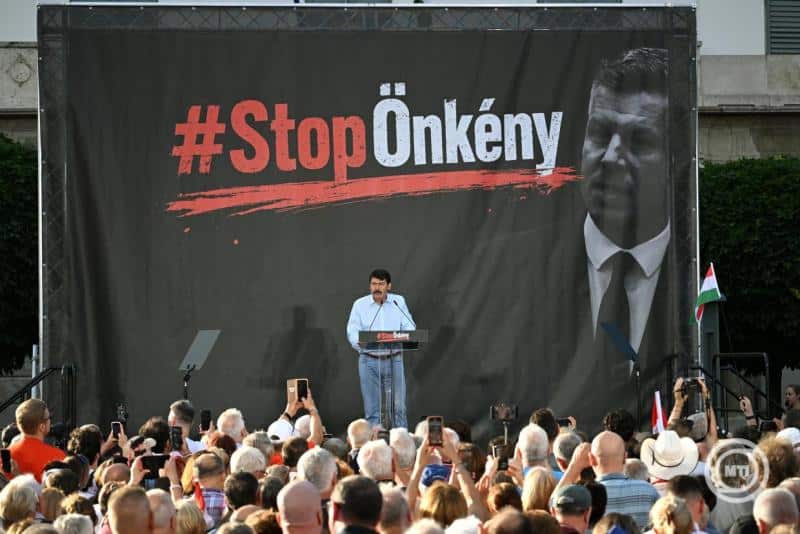 Ember beszédet mond egy tüntetésen, háttérben nagy #StopÖnkény felirat.