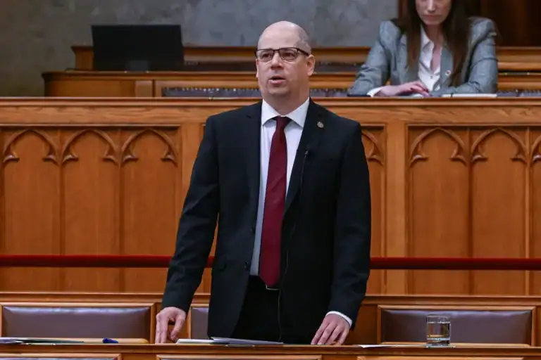 Magyar politikus beszél a parlamentben, háttérben más képviselők.