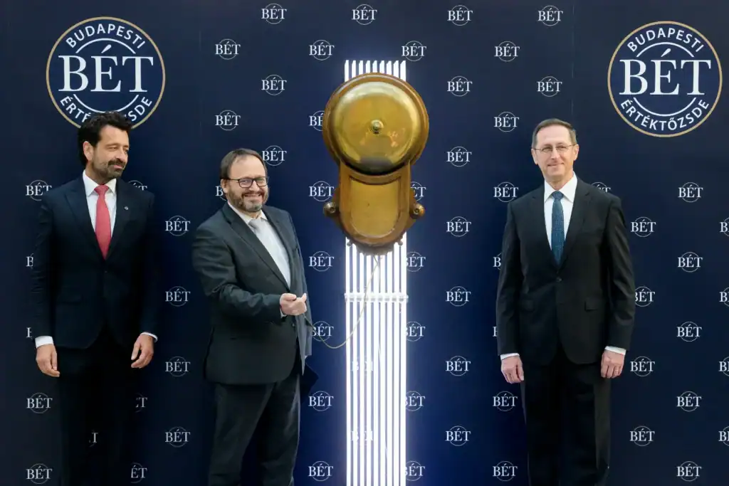 Három férfi áll egy színpadon, egy nagy arany kulcs előtt.