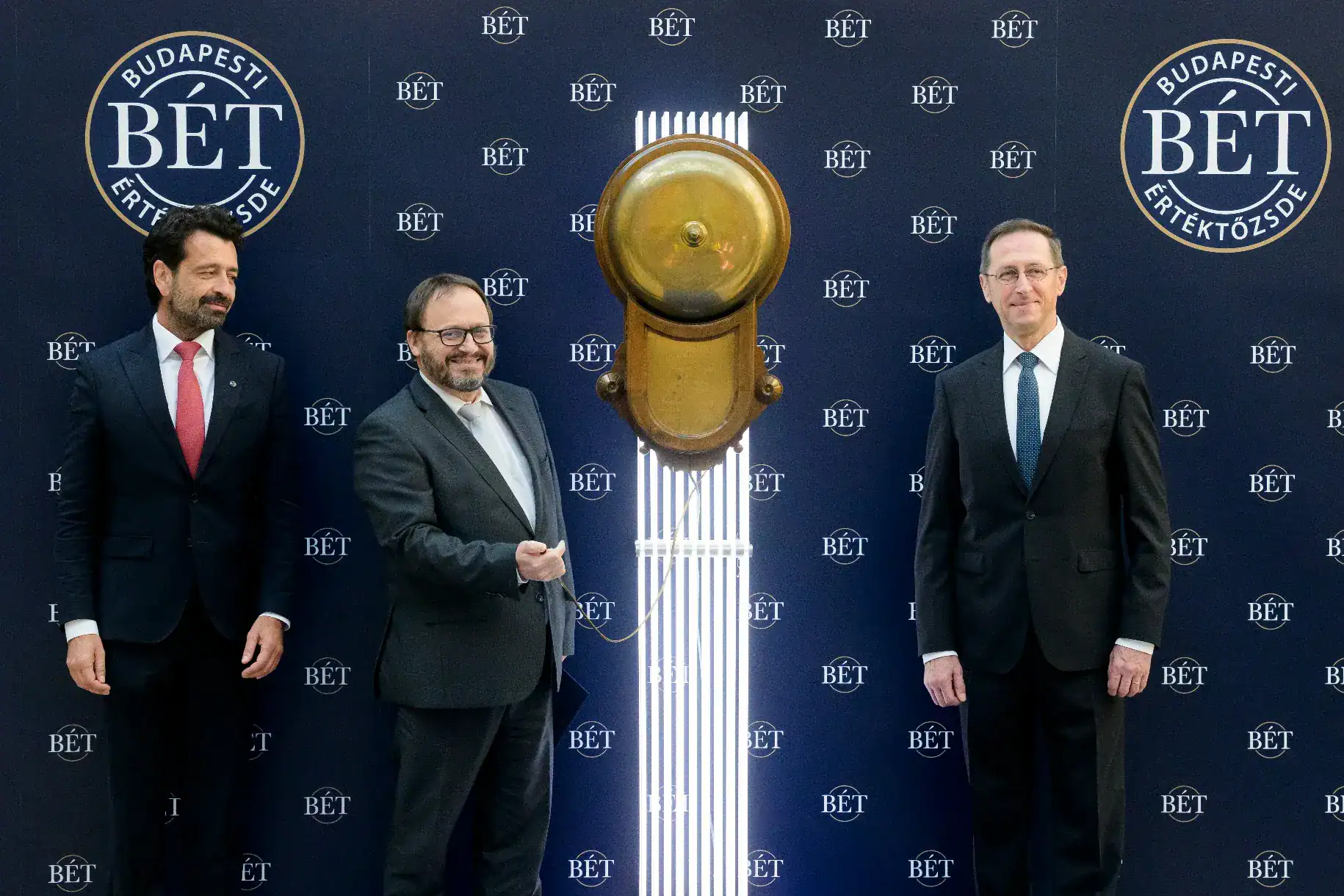 Három férfi áll egy színpadon, egy nagy arany kulcs előtt.